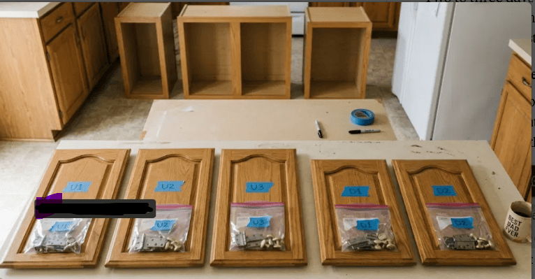 Labeled cabinet doors laid out with matching numbered bags of hinges and screws on a protected work surface